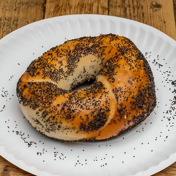 A golden-brown poppy seed bagel from Bagel Culture on a white paper plate.